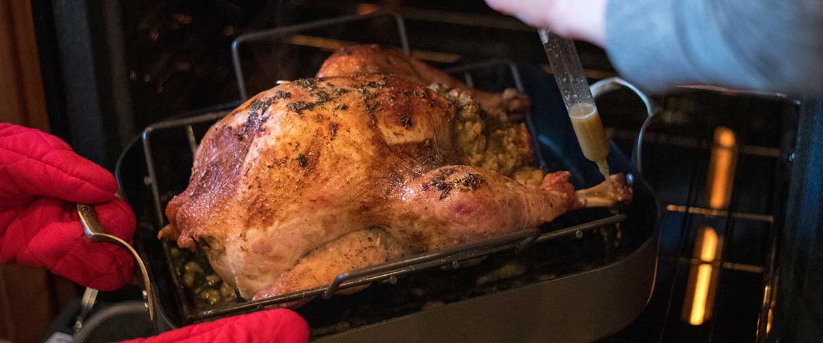 picture of turkey being placed in the oven on a braising pan
