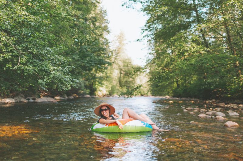 A woman is smiling as she floats on a river in a tube